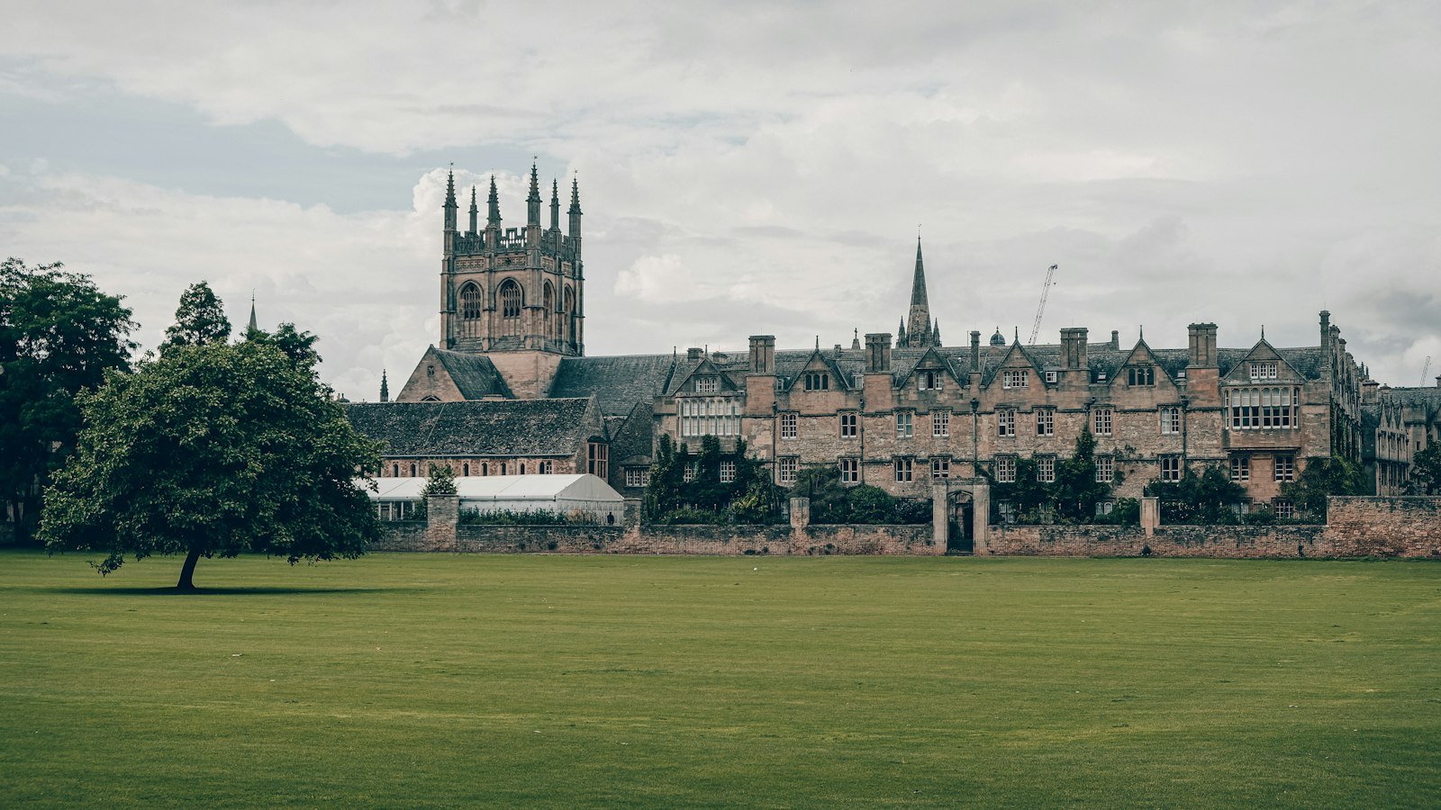 Historic college building behind a wide green lawn in England